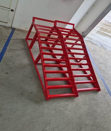 A red ladders on a concrete floor

Description automatically generated